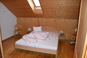 a bedroom with a white bed with a wooden ceiling at Ferienhof Krinde in Ringoldswil