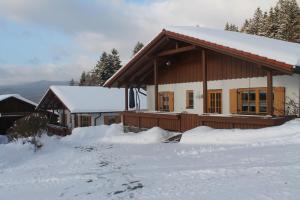 dom ze śniegiem przed nim w obiekcie Familienferienhof Kroner w mieście Zwiesel