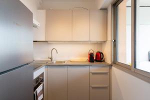 a small kitchen with white cabinets and a sink at Bijou Plage in Juan-les-Pins