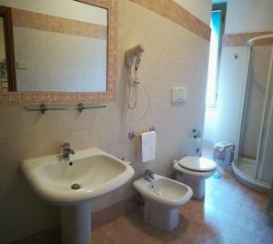 łazienka z umywalką, toaletą i lustrem w obiekcie Hotel Universo w mieście Fiuggi