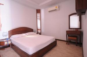 1 dormitorio con cama, tocador y espejo en Paradise Inn and Dining, en Saraburi