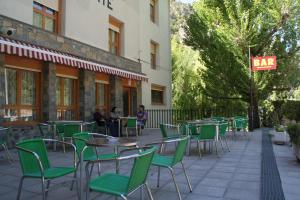 eine Außenterrasse mit grünen Stühlen und Tischen sowie eine Bar in der Unterkunft Mesón De Salinas in Salinas de Bielsa