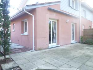 ein rosafarbenes Haus mit einer Terrasse in der Unterkunft 18 Résidence Parc de la Dune in Lacanau