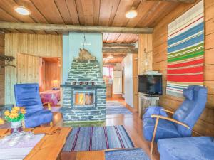 - un salon avec une cheminée en pierre et des chaises bleues dans l'établissement Holiday Home Viehko by Interhome, à Lipinlahti