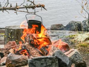 a fire pit with a pot on a tree stump at Holiday Home Viehko by Interhome in Lipinlahti