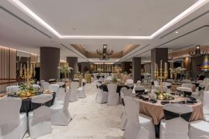 卢萨卡Neelkanth Sarovar Premiere的宴会厅配有桌子、白色椅子和宴会