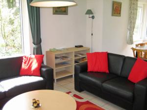 a living room with two black couches and red pillows at Holiday Home Bosrijk Ruighenrode-5 by Interhome in Lochem