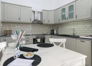 a kitchen with white cabinets and a white table and chairs at Uncle's House luxury Suites in Adamas