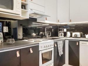 a kitchen with white cabinets and a stove top oven at Holiday Home Karhunvartijan linna c17 by Interhome in Ruka