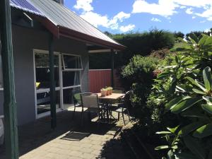 een patio met een tafel en stoelen in een tuin bij Self contained and private room in Dunedin