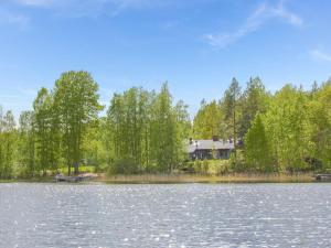 a view of a lake with a house in the background at Holiday Home Viehko by Interhome in Lipinlahti