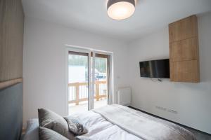 a bedroom with a bed and a television on a wall at ff apartments Jasná Lúčky in Demanovska Dolina