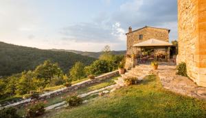 a stone building with a tent on a hill at Borgo Livernano - Farmhouse with pool in Radda in Chianti