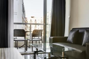 un soggiorno con divano e tavolo in vetro di The Village Apartments a San Pawl il-Baħar