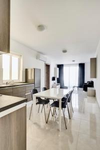 a kitchen and dining room with a table and chairs at The Village Apartments in St Paul's Bay