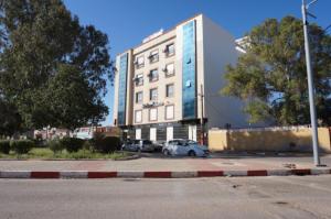 duży budynek z samochodami zaparkowanymi na parkingu w obiekcie MARAVAL w mieście Oran
