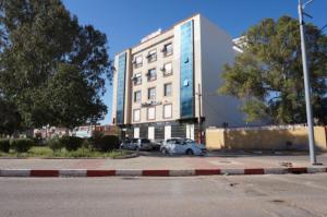ein großes Gebäude mit auf einem Parkplatz abgestellten Autos in der Unterkunft MARAVAL in Oran