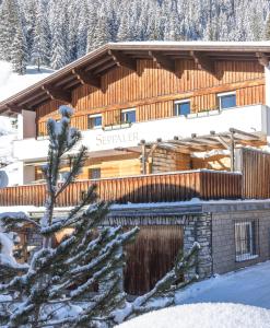 un lodge dans la neige avec un arbre en face dans l'établissement SkiLodge Seppaler, à Sankt Anton am Arlberg