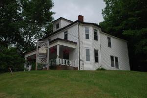 une vieille maison blanche avec terrasse couverte sur une colline dans l'établissement Awakenings Inn, à Montague