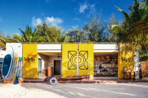 un edificio amarillo con una tabla de surf pintada en él en Zuri Zanzibar, en Kendwa