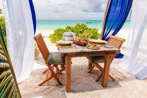 a table with food on a beach with the ocean at Zuri Zanzibar in Kendwa
