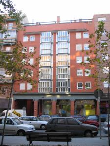 un gran edificio rojo con coches estacionados en un estacionamiento en ARGANZUELA, en Madrid