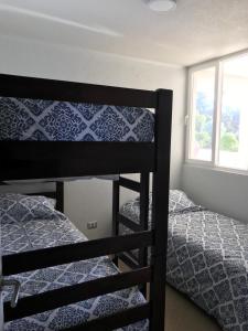 1 dormitorio con 2 literas y ventana en Costa Quilén - Vista al Mar Dpto 241 en Puchuncaví