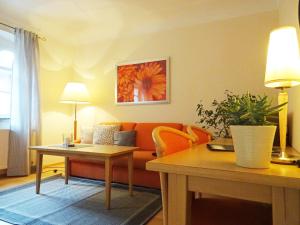 a living room with an orange couch and a table at Ferienwohnung, Weingut Trockene Schmitts in Randersacker