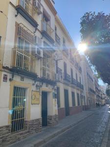 a building on the side of a street with the sun at Giraldilla in Seville