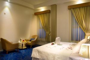 Habitación de hotel con 1 cama y 2 sillas en Fiori Hotel Suites, en Al-Hasa
