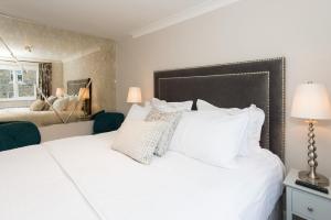 1 dormitorio con 1 cama blanca grande con almohadas blancas en The Mews, York Place by Harrogate Serviced Apartments, en Harrogate