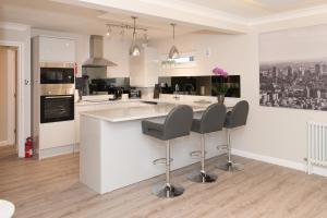 een keuken met een wit aanrecht en 2 krukken bij The Mews, York Place by Harrogate Serviced Apartments in Harrogate