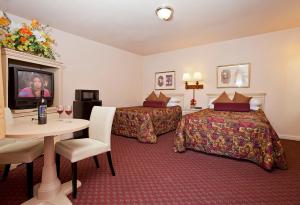 pokój hotelowy z dwoma łóżkami i stołem z telewizorem w obiekcie El Camino Inn w mieście Daly City