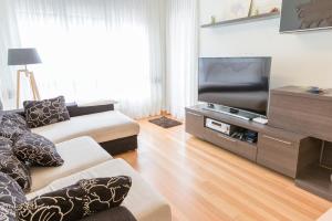 a living room with a couch and a flat screen tv at Apartamento Ria de Boo, Con patio privado in Boó de Piélagos