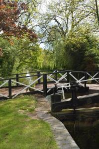 un puente sobre un río con árboles y césped en Bucket Lock Cottage, en Warwick