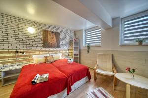 una camera con letto rosso, tavolo e sedia di Fox Rooms Aparthotel a Stara Zagora