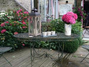 - une table avec des fleurs et une lanterne sur la terrasse dans l'établissement Chambres d'Hôtes Côté Campagne, à Vaux-sur-Aure