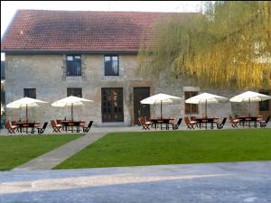a group of tables with umbrellas in front of a building at auberge du pied des monts in Grivy-Loisy