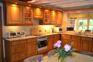 a kitchen with wooden cabinets and a table with flowers at Bucket Lock Cottage in Warwick