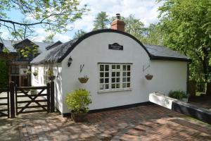 a small white house with a black roof at Bucket Lock Cottage in Warwick