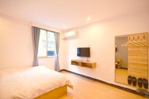 a bedroom with a bed and a tv and a mirror at Guilin Cyan Box Guest House in Guilin