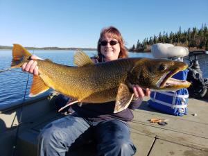 une femme assise sur un bateau tenant un gros poisson dans l'établissement Lake Louise Lodge, Alaska, à Glennallen