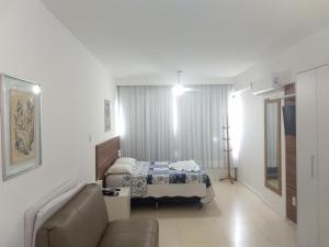 Habitación de hotel con cama y sofá en Flat na Avenida Oceanica, en Salvador