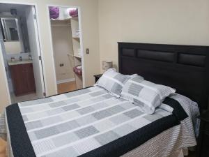 Cama con sábanas y almohadas blancas y grises en Cuatro Norte 955 Apartamento Full equipado, en Talca