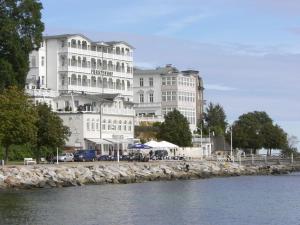 a large white building next to a body of water at Komfortferienwohnungen Sassnitz in Sassnitz