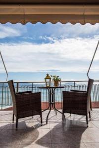 two chairs and a table on a balcony with the ocean at Hotel Assini Beach Tolo in Tolo