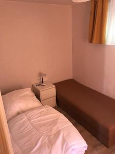 a small bedroom with a bed and a night stand at Domek Parterowy in Gąski