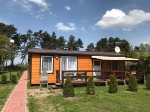 a tiny house with a porch and a lawn at Domek Parterowy in Gąski