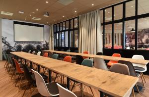 a conference room with tables and chairs and a projection screen at Ibis budget Dijon Centre Clemenceau in Dijon
