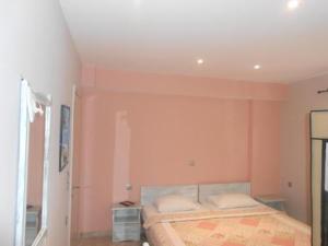 a bedroom with pink walls and a bed with two pillows at Hotel Assini Beach Tolo in Tolo